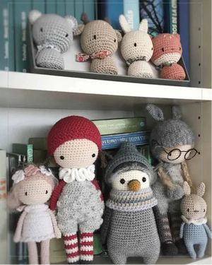 Collection of crocheted dolls on a shelf with 'L'auteure' branding.